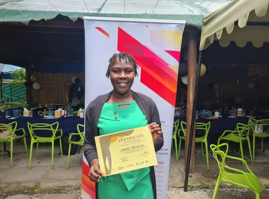 A fellow proudly holds up her certificate at the IAWRT Kenya fellowship graduation