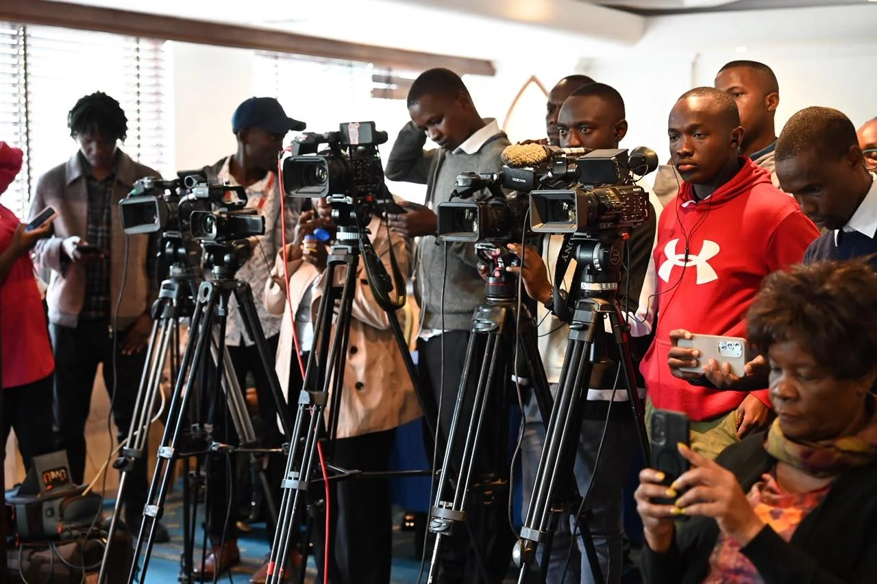 Camera operators and journalists with cameras on tripods at a press event