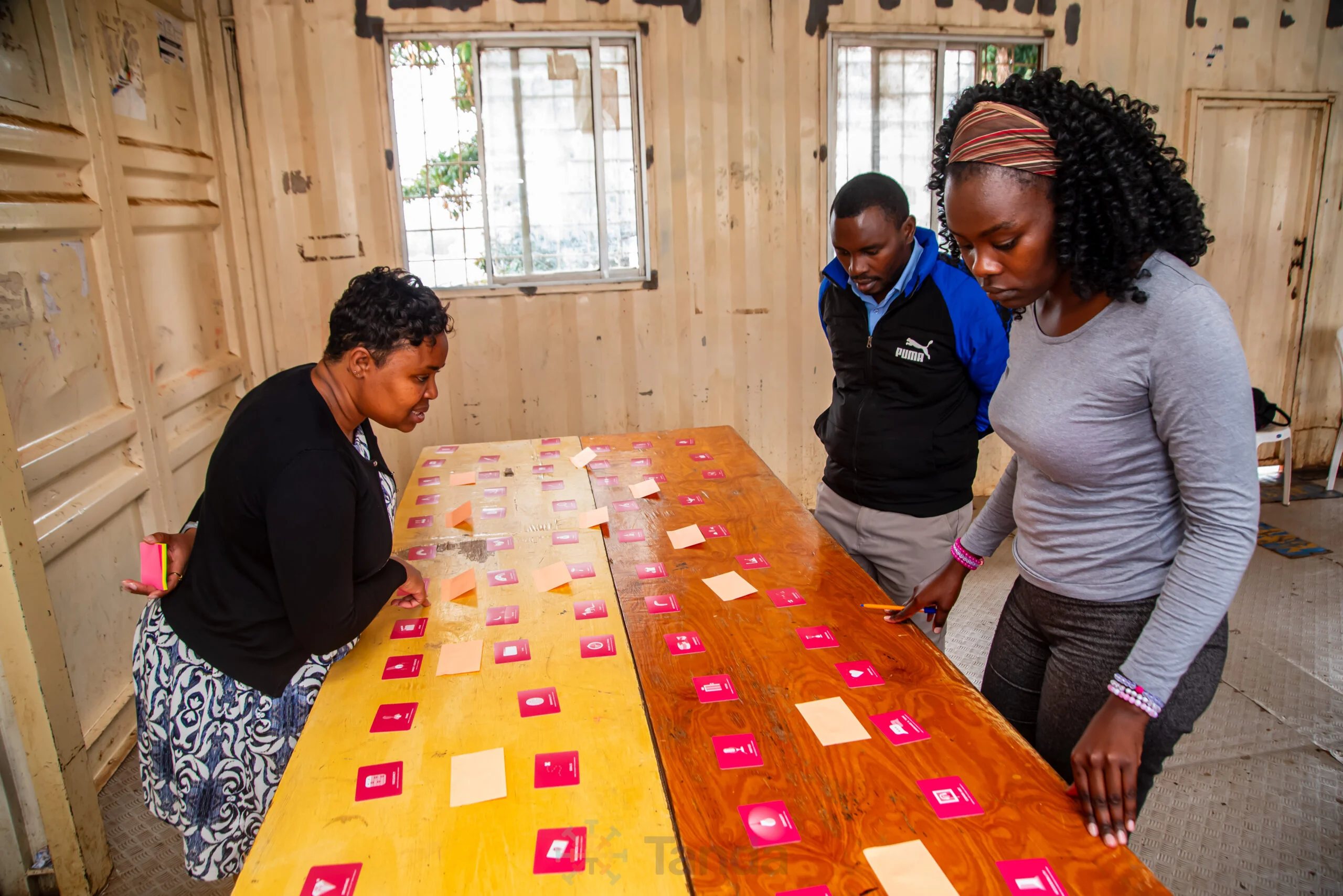 Women arrange cards on a table during a participatory research session