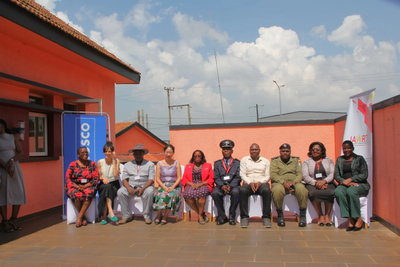 Participants seated in a row for a group photo at an outdoor event with a UNESCO banner
